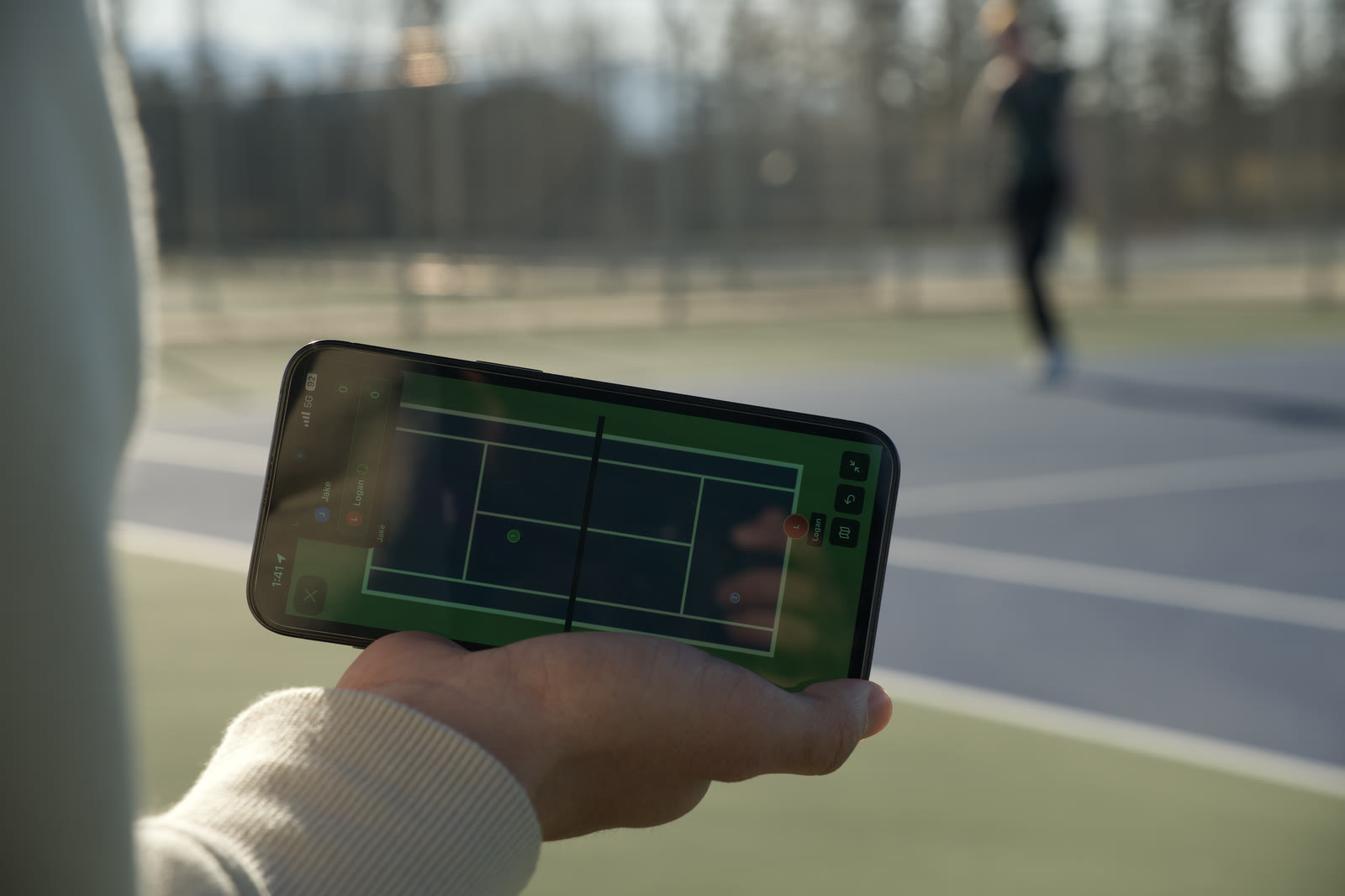 A phone held above the court while a teammate moves in the background