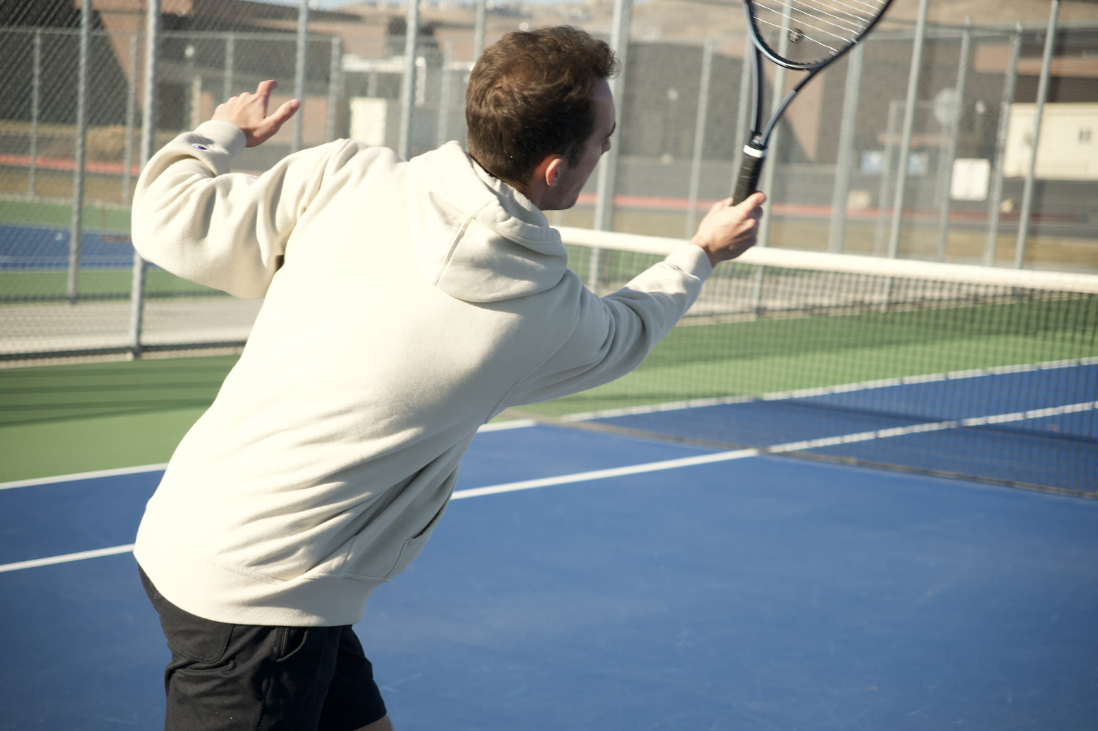 A player reaching overhead at the net in low sun